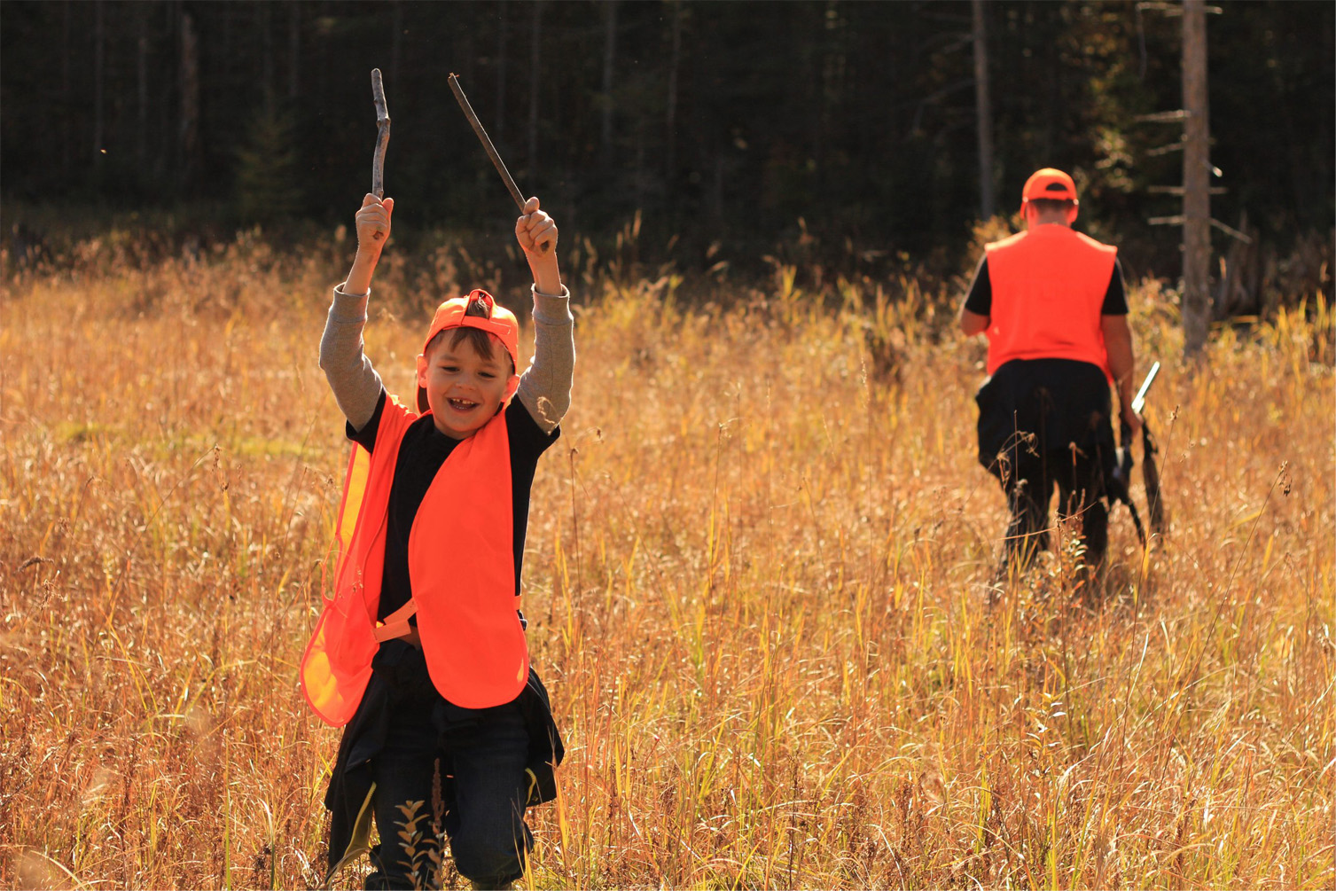 Kids hunting laughing wearing orange with sticks